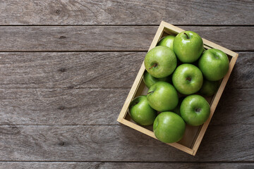 Green apple in wooden box isolated on table background with copy space, top view, flat lay.