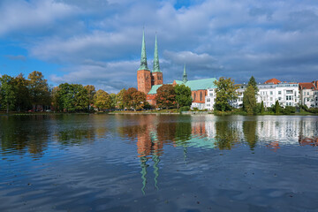 Lubeck, Germany. View of Lubeck Cathedral from the opposite shore of Muhlenteich (Mill pond) in autumn day. The cathedral was started in 1173 and consecrated in 1247. - 763247981