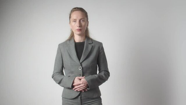 An adult woman in a gray business suit stands on a white background