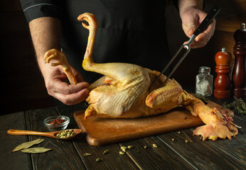 Cooking chicken in the pub or saloon kitchen by the cook. Raw chicken on a cutting board. Fork in...