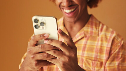 Close-up, guy's hands holding mobile phone, isolated on brown background, soft focus