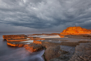 sunset light and unique shaped cliffs by the sea colorful clouds in the sky