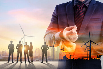Double exposure of businessman and silhouette of business team with wind turbine far at sunset 