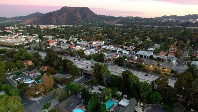 Aerial Scenic View Of Residential Houses In City By Mountains, Drone Flying Backwards During Sunset - Burbank, California