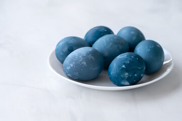 Blue colored Easter eggs on white table on neutral marble table background, traditional Easter holiday homemade decorated food, soft selective focus