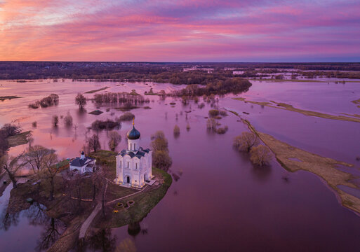 Aerial view of flooded Nerl river with Church of the Intercession on the Nerl in beautiful orange and purple sunset, Vladimir, Russia.