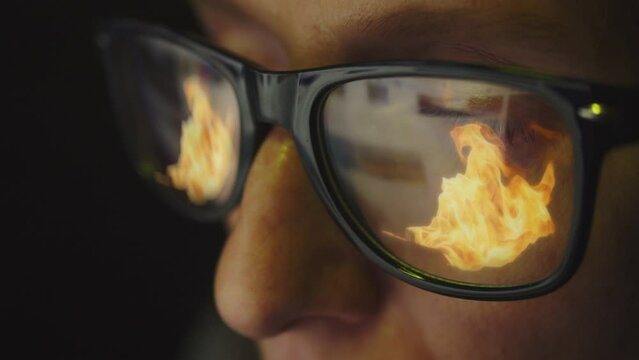 In the reflection of glasses on a female face there is an Internet search engine and a burning fire. Flaming news concept. Cg footage