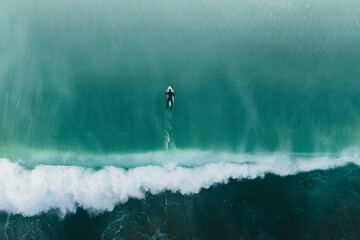 Aerial view of a surfer swimming in the sea, Peniche, portugal.