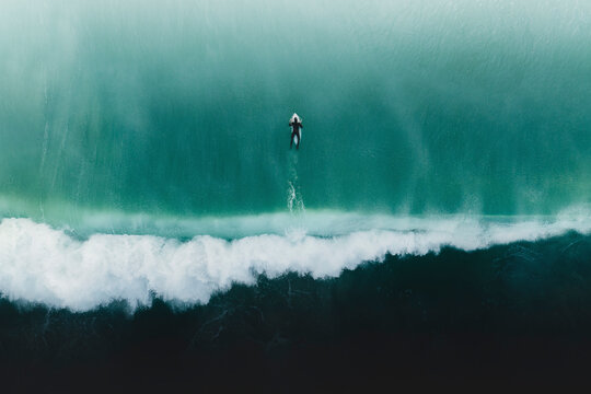 Aerial view of a surfer immersed in the colors of the sea in Peniche, Portugal.