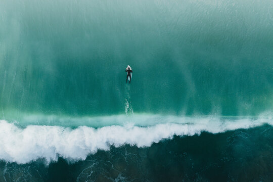 Aerial view of a surfer swimming in the sea, Peniche, portugal.