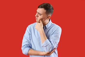 Young man suffering from toothache on red background
