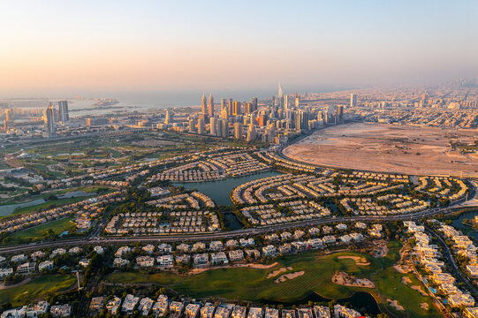 Aerial view of Jumeirah Golf Club and upscale residential area with green spaces, lake, and palm trees, Dubai, United Arab Emirates.