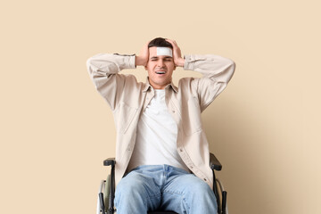 Young man with brain concussion in wheelchair on beige background