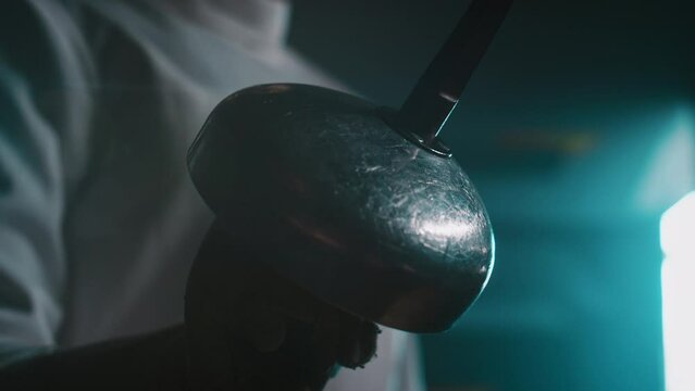 Closeup of anonymous fencer holding foil sword in hand indoors