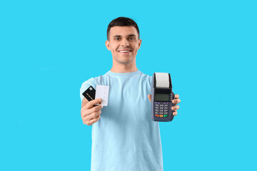 Male online store seller with credit cards and payment terminal on blue background