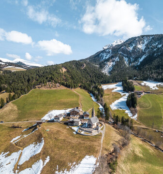 Aerial view of Val di Funes with beautiful dolomites, lush forests and Santa Maddalena church, South Tyrol, Italy.