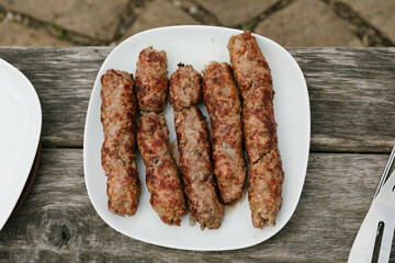 plate of grilled sausages on wooden background.  Top view. Barbecue sausages presented on the fire.
