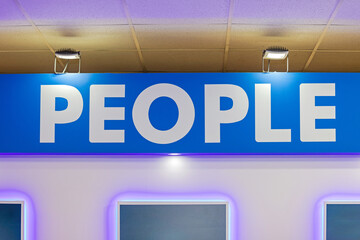 Big Sign People White Letters at Blue Background Illuminated With Reflectors