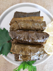 Delicious traditional oriental dolma made of grape leaves stuffed with rice on a plate with parsley...