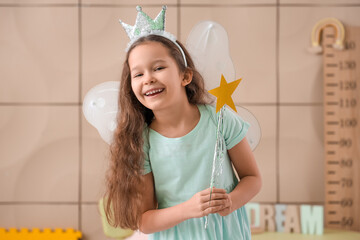 Little girl dressed as fairy with wand at home