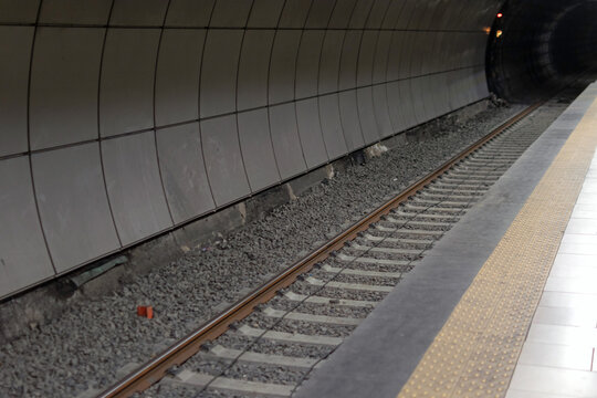 Railway metal rails and concrete sleepers for a metro train on gray gravel inside the underground metro station