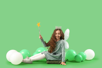 Cute little fairy with wand and balloons sitting on green background