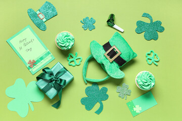 Leprechaun hat with cupcakes, gift box and decor on green background. St. Patrick's Day celebration
