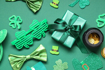 Gift box with plastic eyeglasses, bow tie and decor for St. Patrick's Day on green background