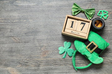 Leprechaun hat with calendar and bow tie on grey wooden background. St. Patrick's Day celebration