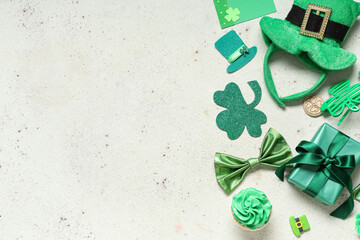 Leprechaun hat with cupcake, gift box and decor for St. Patrick's Day on white grunge background