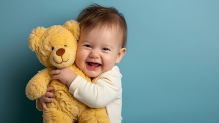a baby holding a teddy bear in his arms on a grey background