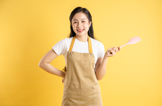 Portrait of Asian housewife girl posing on yellow background