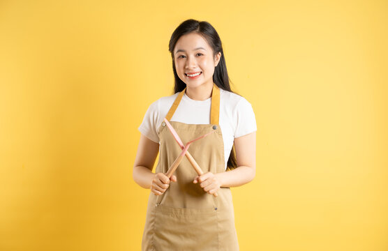 Portrait of Asian housewife girl posing on yellow background