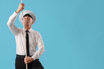 Mature sailor with rope on blue background
