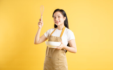 Portrait of Asian housewife girl posing on yellow background