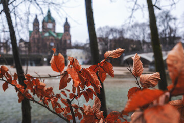 St. Luke's Church seen behind the dried autumn leaves around the Isar River, Munich, Germany