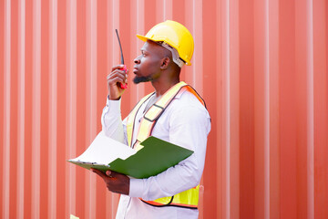 Engineer wearing safety helmet working in shipping container industry.