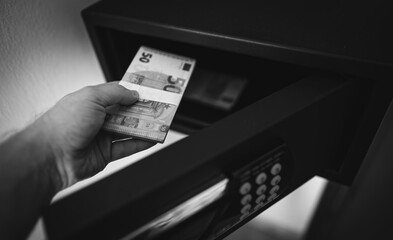 Man puts or takes euro banknotes from a safe. - 763285399