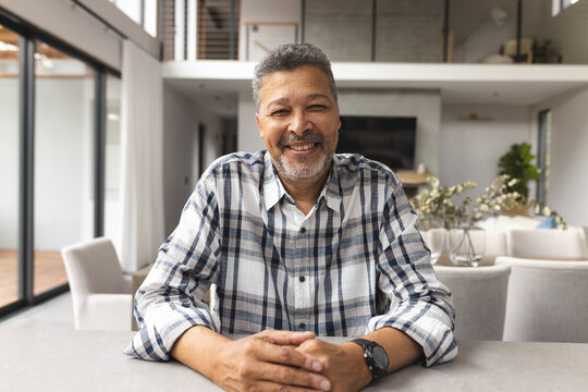 A senior biracial male is smiling at the camera in a video at home