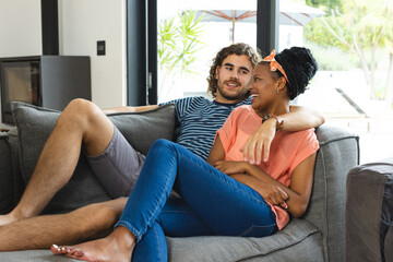 Obraz premium A diverse couple is relaxing together on a gray sofa at home