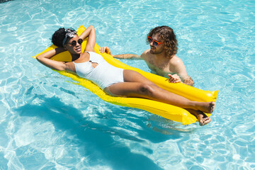 A diverse couple enjoys sunny day in pool