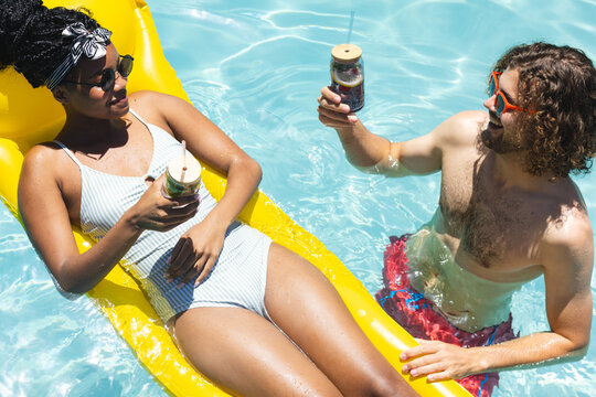 A diverse couple enjoys drinks in pool