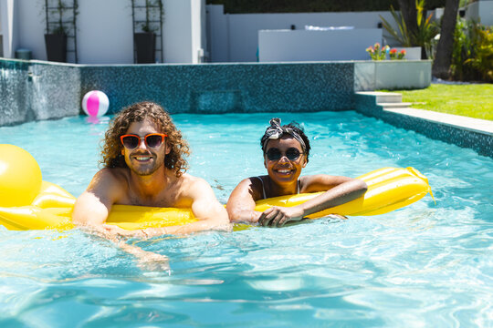 A diverse couple enjoys sunny day in pool - Powered by Adobe