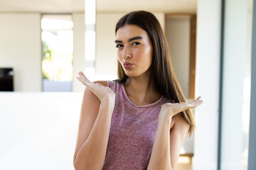 A young Caucasian brunette woman is blowing a kiss at home