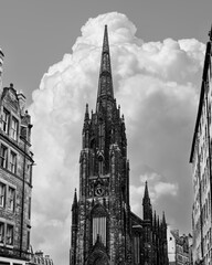Black and white capture of Edinburgh skyline dominated by the Hub towering gothic spire, perfectly aligned with the rising cumulus clouds