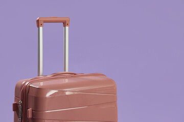 Pink suitcase on lilac background, closeup