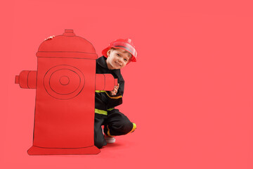 Cute little firefighter with paper hydrant on red background