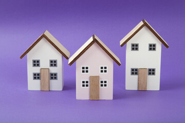 a group of 3 miniature houses lined up on a bright purple background