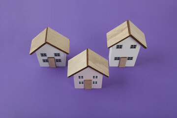 a group of 3 miniature houses lined up on a bright purple background