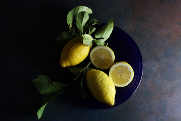 Limoni su un piatto blu; still life con vista dall’alto, composizione su fondo scuro